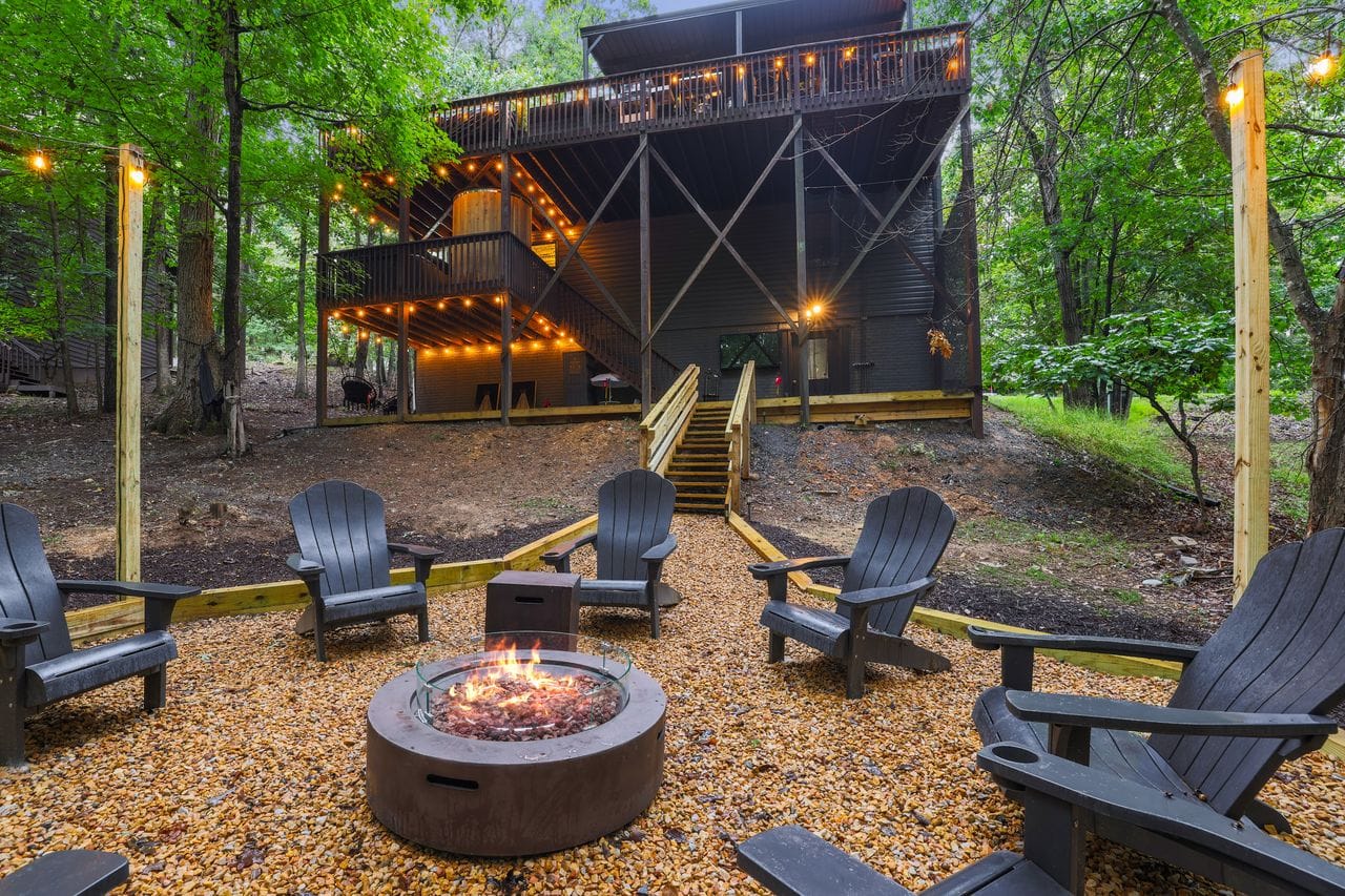 Rear exterior at twilight, decks stacked above the fire pit clearing